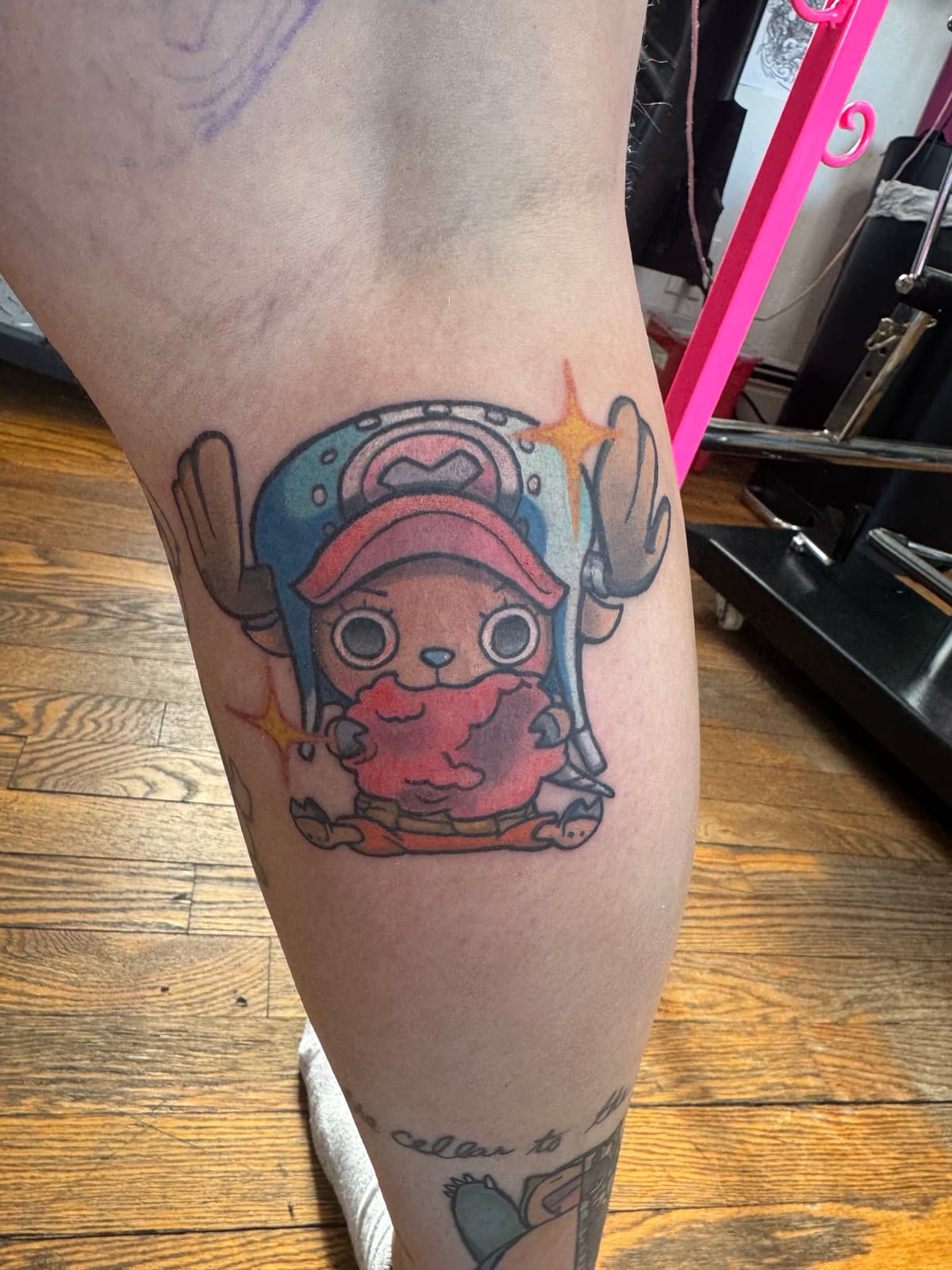 Tony Tony Chopper from One Piece tattoo on calf — chibi form, blue hat with pink fur, sparkles.