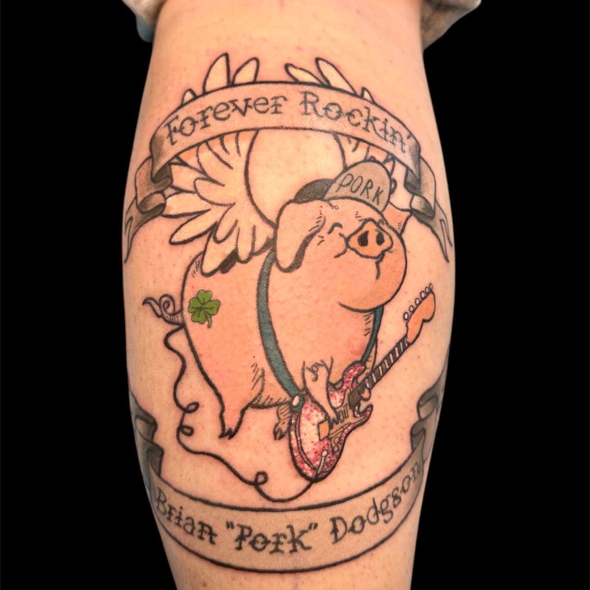 Memorial tattoo for Brian "Pork" Dodgson — a flying pig with angel wings, halo, and PORK cap playing electric guitar, with "Forever Rockin'" and the name on banners.